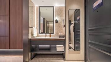 A modern bathroom with a large mirror, a sink, and a shower area.