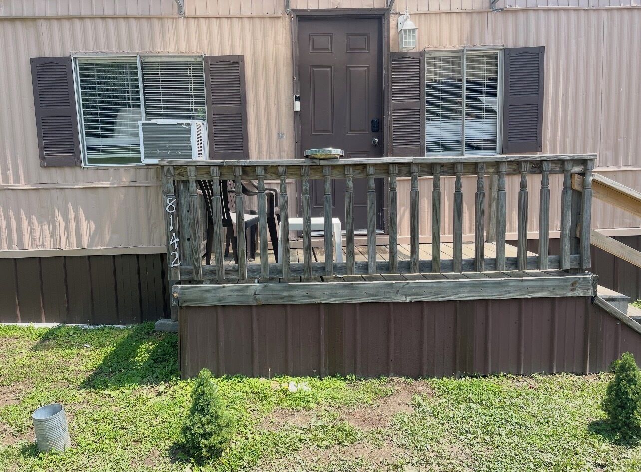 A residential building with a wooden deck, a door, and a window with shutters.