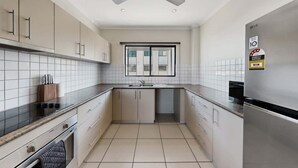A modern kitchen with a built-in oven, a stainless steel refrigerator, and a window above the sink. - Peaceful 2-Bed Apartment with Private BBQ Balcony (Rosebery)
