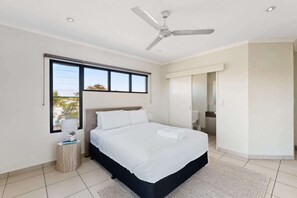 A modern bedroom with a bed, a ceiling fan, a window, and a view of the outdoors. - Peaceful 2-Bed Apartment with Private BBQ Balcony (Rosebery)