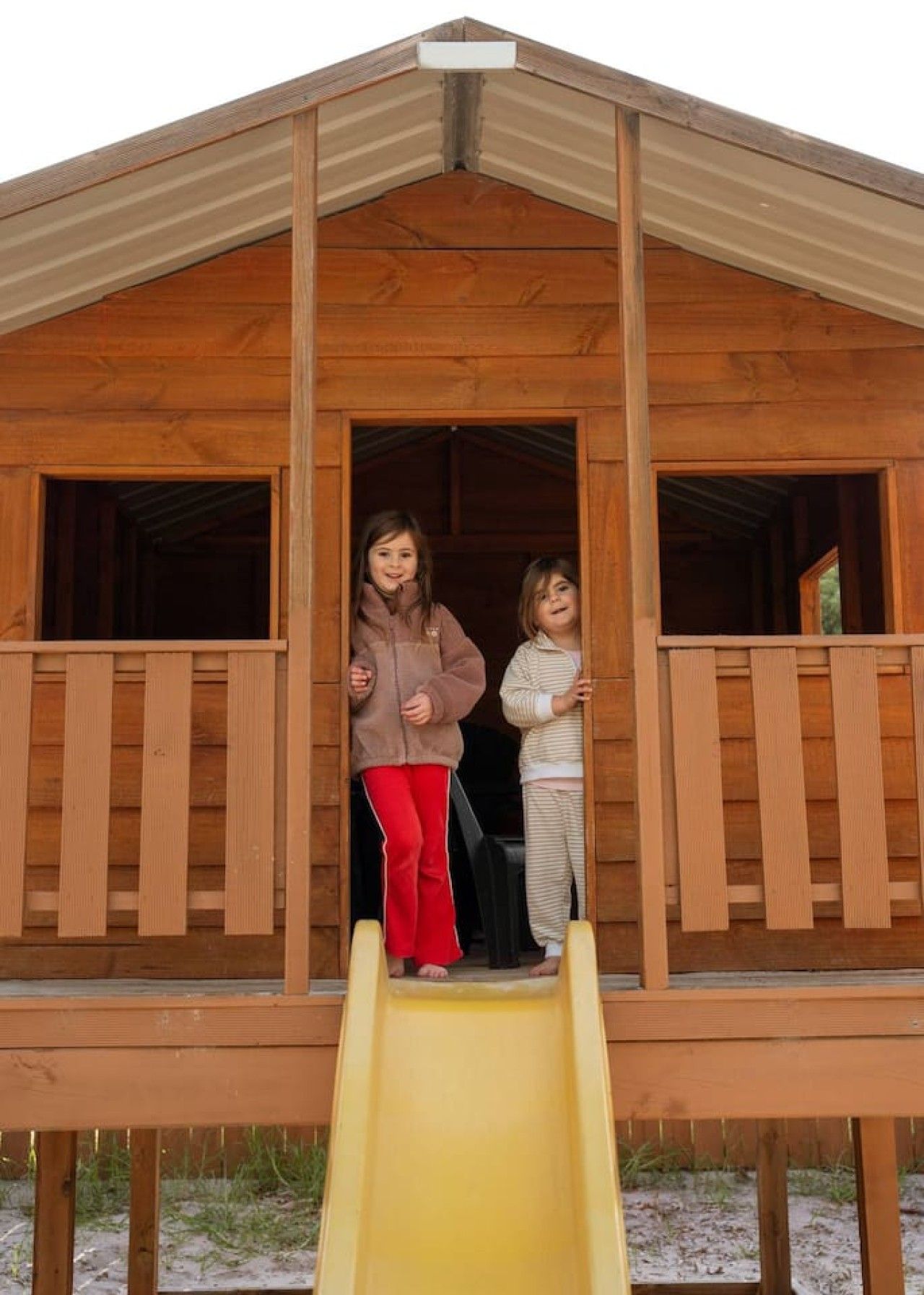 A wooden playhouse with a yellow slide.
