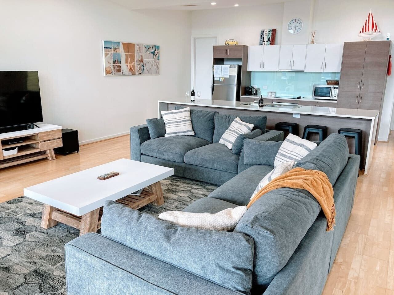A modern living room with a sectional sofa, a coffee table, and a TV.