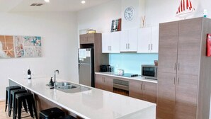 Una cucina moderna con isola centrale, sgabelli da bar, frigorifero, microonde e pensili.