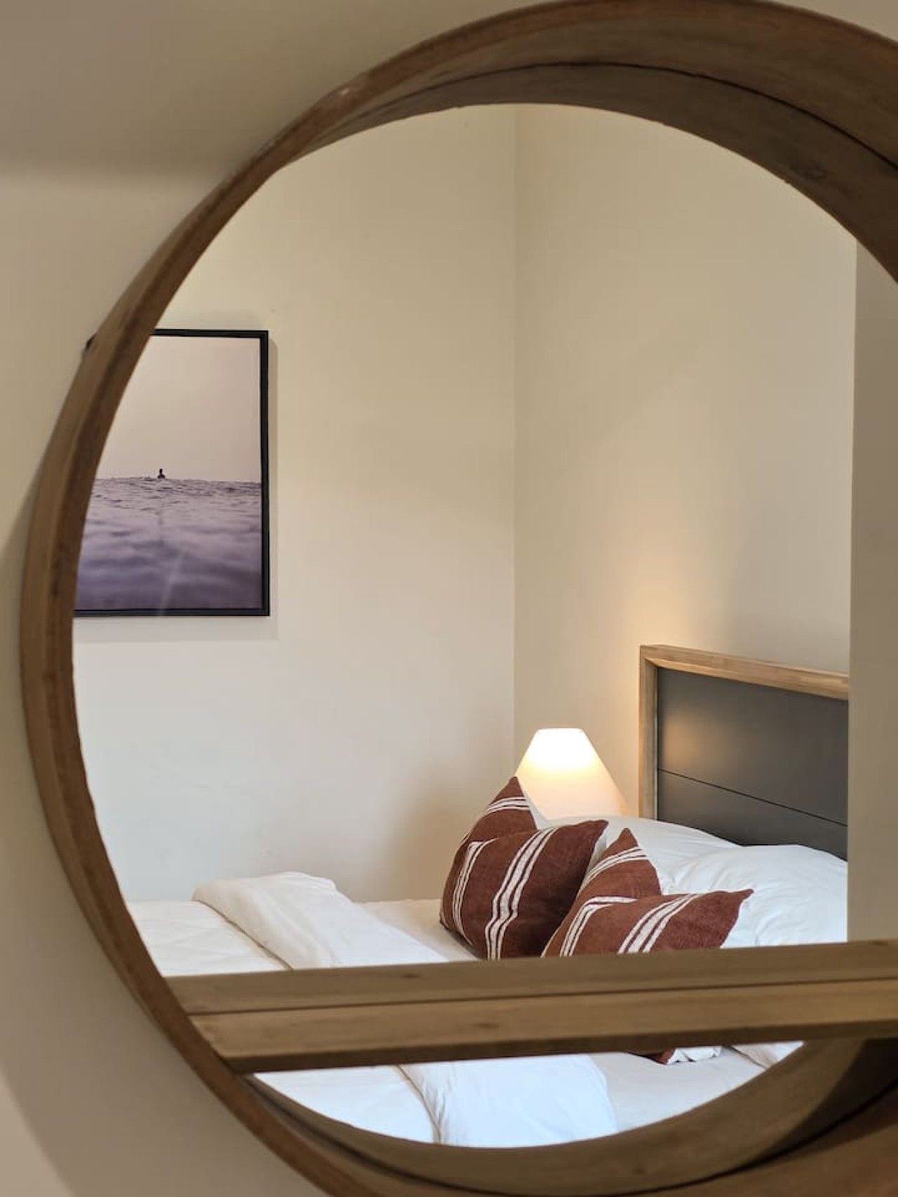A bedroom with a bed, a lamp, and a framed picture on the wall.