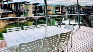 Una terrazza con tavolo e sedie che si affaccia su una distesa d'acqua con edifici sullo sfondo.