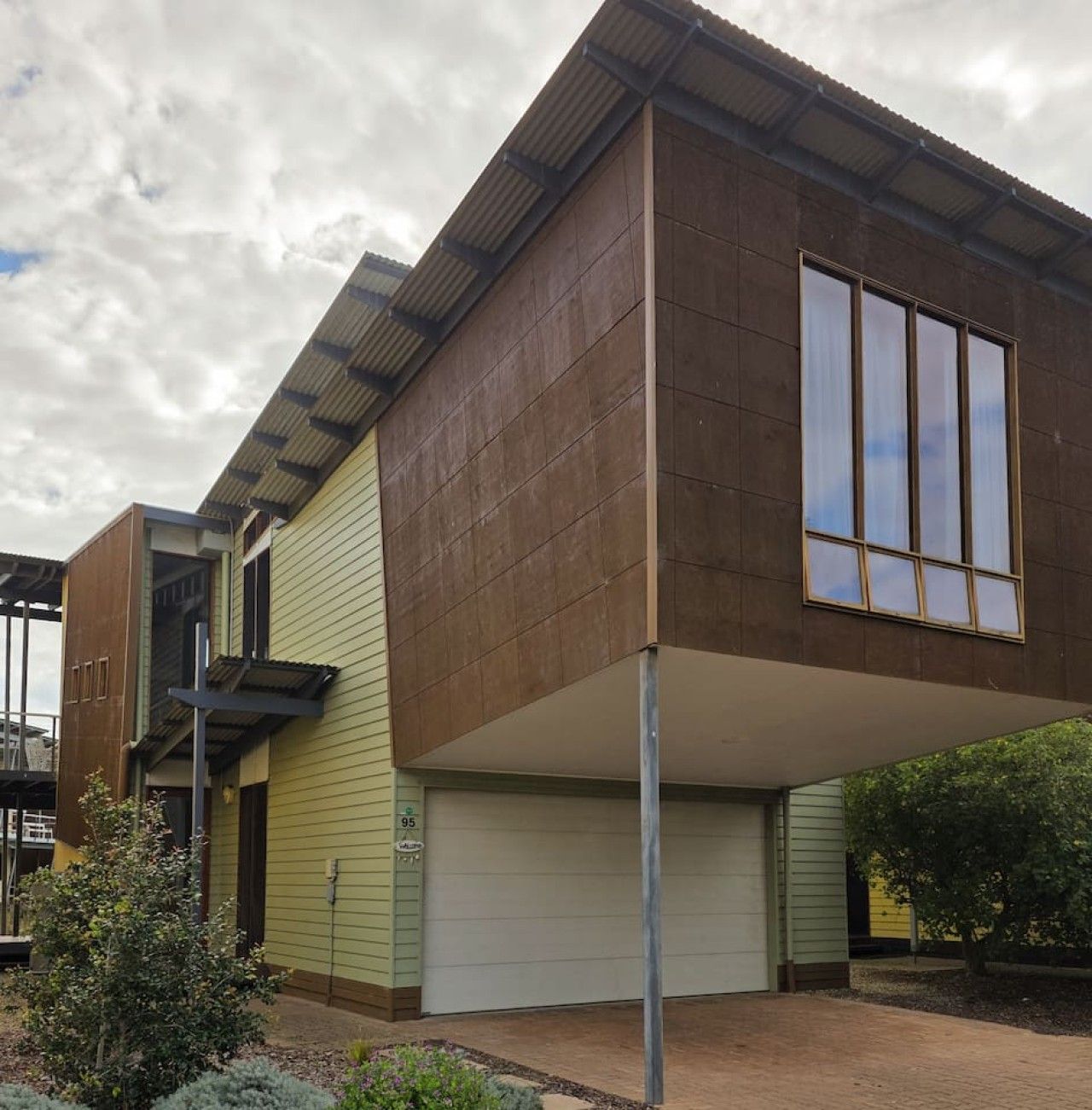 A modern two-story house with a garage, a visible staircase, and a clear sky.