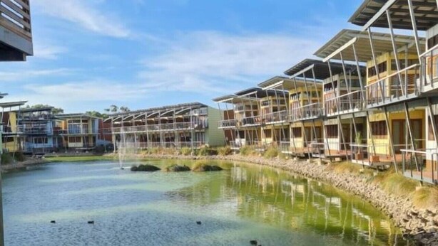 Un hotel sul fiume con numerosi balconi, vista libera sul fiume e una passerella coperta.