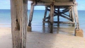 Una banchina di legno con una spiaggia sabbiosa e acqua calma sullo sfondo.