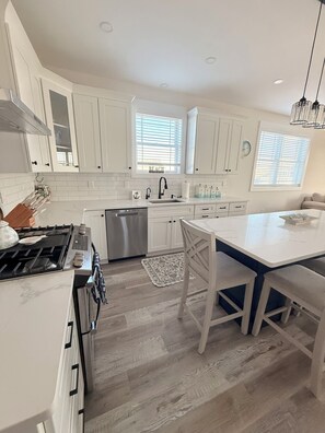 A modern kitchen with white cabinetry, a stainless steel range, and a central island with seating. - 3000 sq. ft, 4-BR, 4 Bath, 3 Blocks to the ocean beach house in Seaside Heights. (Seaside Heights)