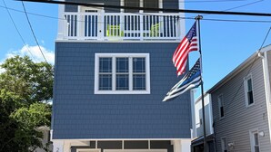 Um prédio de dois andares com garagem, varanda e a bandeira americana.