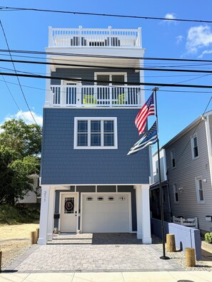 A two-story building with a garage, a balcony, and an American flag. - 3000 sq. ft, 4-BR, 4 Bath, 3 Blocks to the ocean beach house in Seaside Heights. (Seaside Heights)
