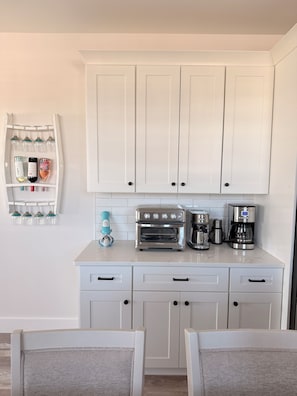 A kitchen with white cabinets, a toaster oven, a coffee maker, and a wine rack with glasses. - 3000 sq. ft, 4-BR, 4 Bath, 3 Blocks to the ocean beach house in Seaside Heights. (Seaside Heights)