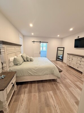 A bedroom with a large bed, a dresser, a mirror, and a television on the wall. - 3000 sq. ft, 4-BR, 4 Bath, 3 Blocks to the ocean beach house in Seaside Heights. (Seaside Heights)