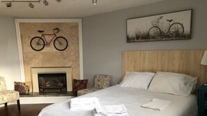Un dormitorio con una cama grande, una chimenea, un cuadro de bicicleta y una mesita de noche.