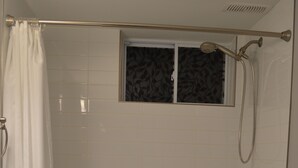 Un baño con bañera, ducha y ventana.