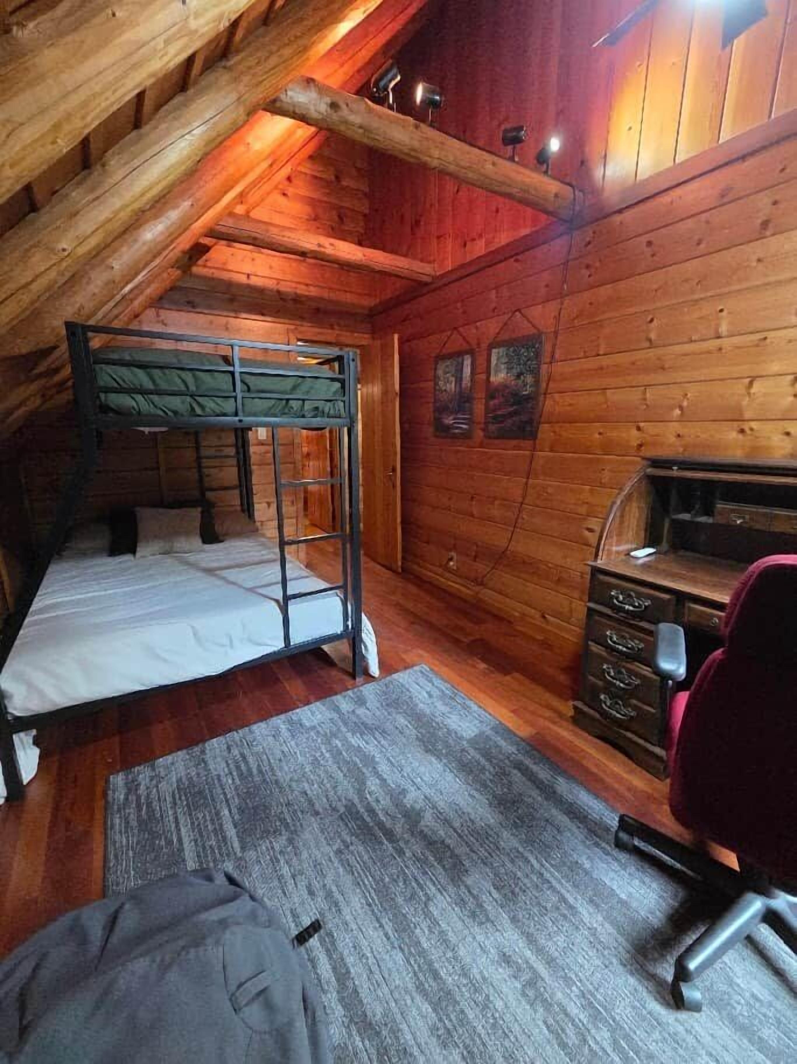 A cabin with a bunk bed, a desk, and a chair.