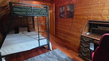 A cabin with a bunk bed, a desk, and a chair.