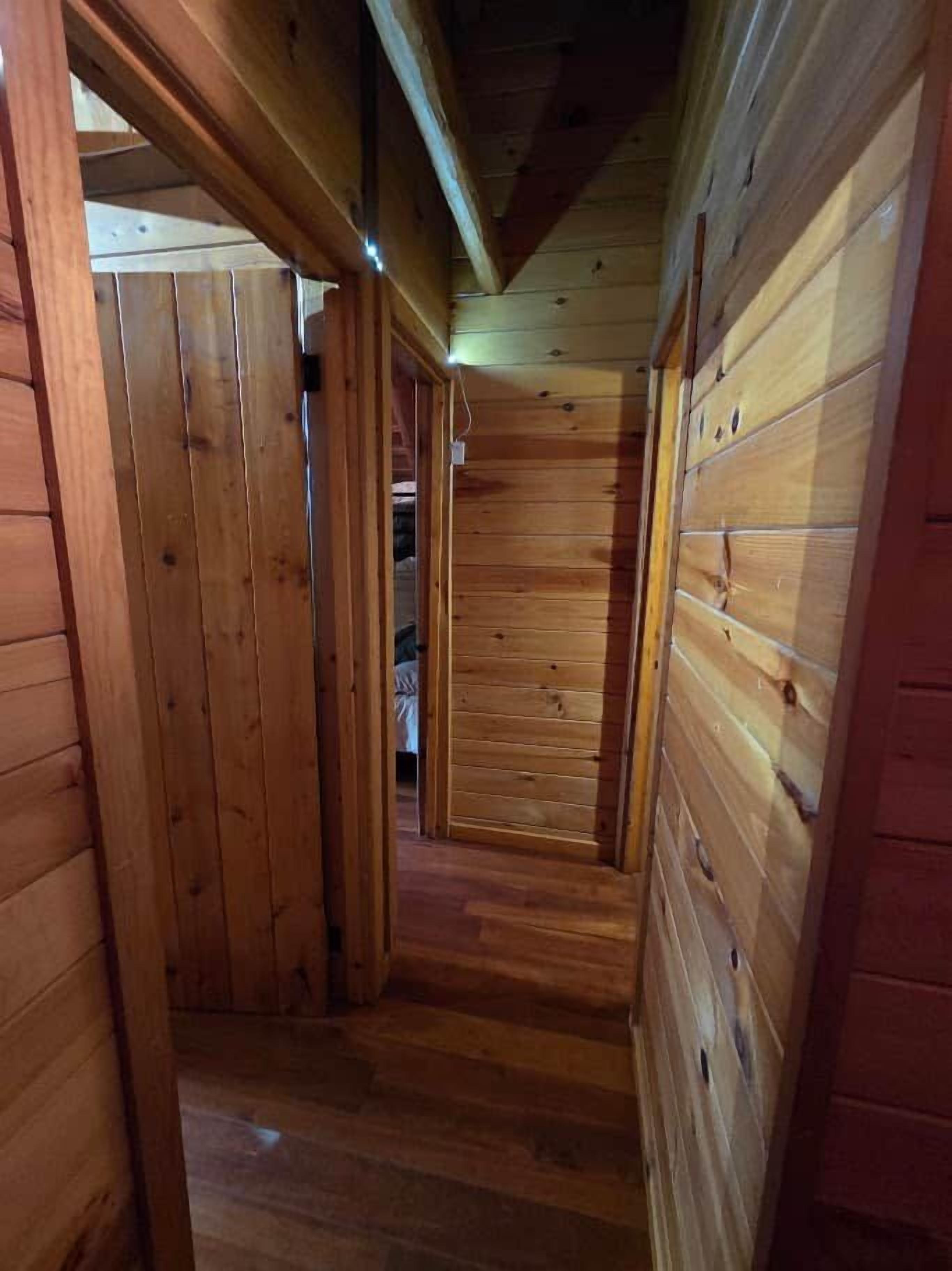 Passadís interior de fusta amb sostre inclinat i parets de fusta.