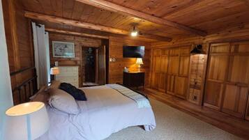 Dormitorio de cabaña de madera con cama, mesita de noche, lámpara y armario.