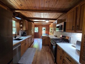 Una cocina con armarios de madera, estufa, microondas y lavaplatos.