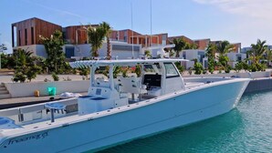 A white yacht docked at a marina with modern buildings and palm trees in the background. - Beachfront 1 Bedroom | Outdoor Pool | Stunning Caribbean Views (Long Bay Hills)