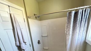 Et badeværelse med badekar, toilet og bruseforhæng.