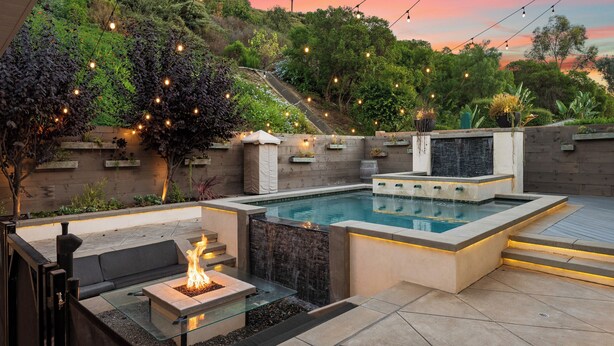 A pool area with a fire feature, seating, and a waterfall. - LA Times "Hot Property" l HGTV Resort Estate near Dana Point Harbor (San Juan Capistrano)