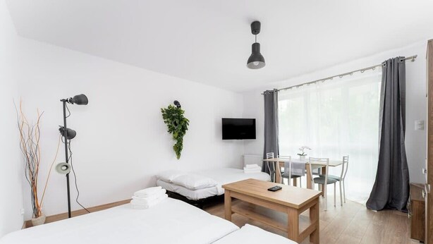 Een moderne hotelkamer met een bed, nachtkastje, televisie en een zithoek met een tafel en stoelen.