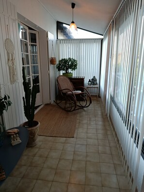 A corridor with a rocking chair, potted plants, and a hanging light fixture. - Time Regained (Saint-Martin-de-Valgalgues)
