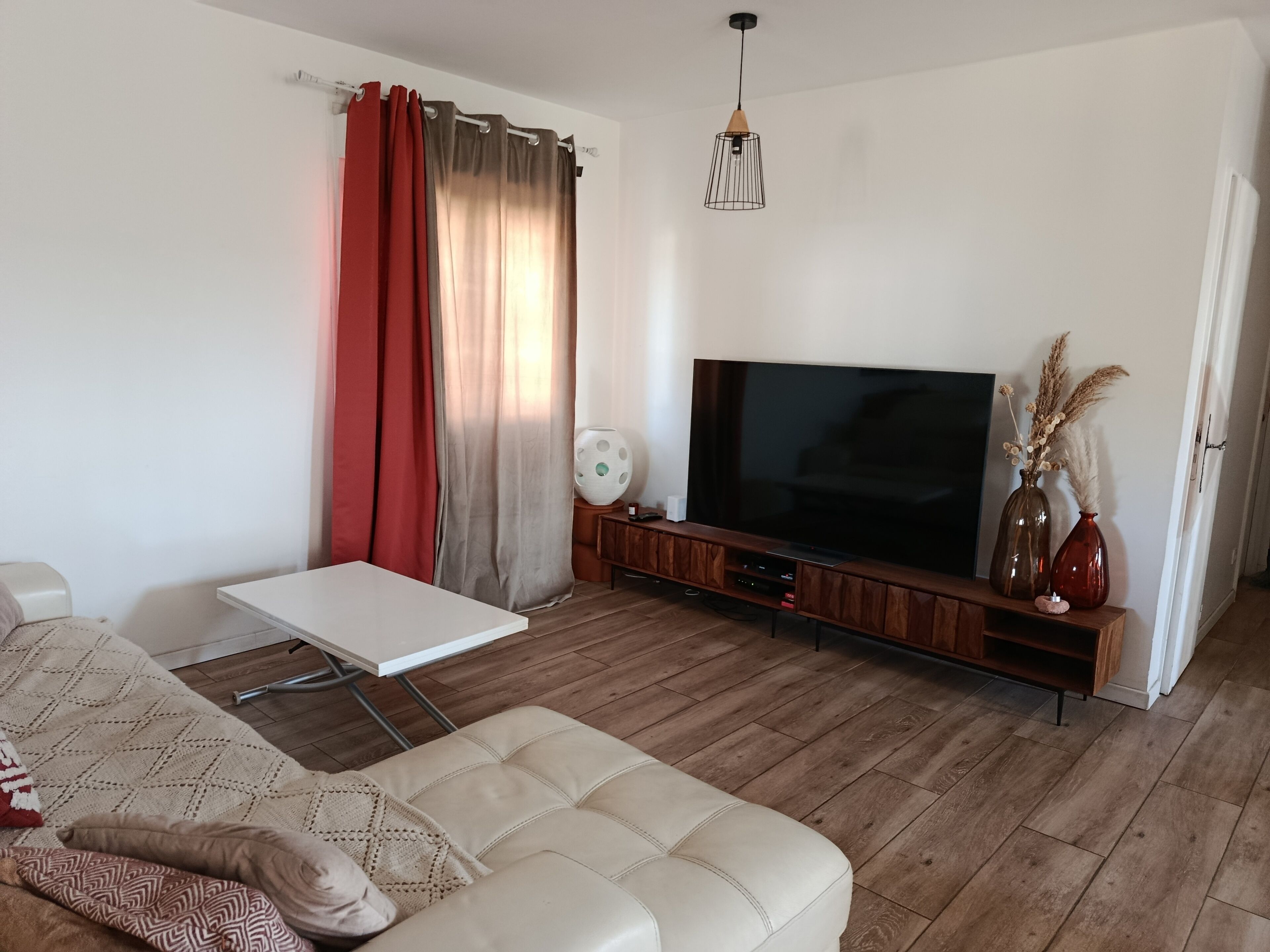 A living room with a sofa, a coffee table, a flat-screen TV, and a wooden entertainment unit.