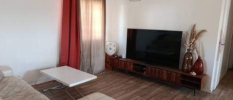 A living room with a sofa, a coffee table, a flat-screen TV, and a wooden entertainment unit.