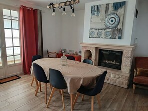 A dining area with a table set for four, a fireplace, and a painting on the wall. - Time Regained (Saint-Martin-de-Valgalgues)