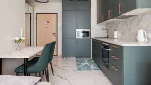 Una cucina moderna con mobili grigi, un piano di lavoro in marmo e una zona pranzo con tavolo e sedie.
