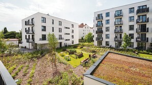 Un complesso residenziale moderno con numerosi balconi, un giardino pensile e un cortile curato.
