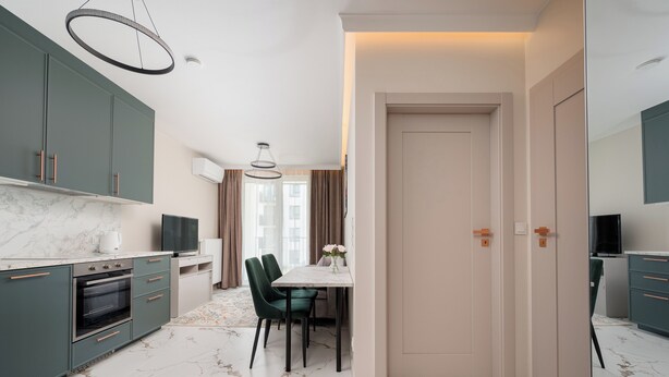 Una cucina moderna con un piano di lavoro in marmo, un'area pranzo con tavolo e sedie, e un corridoio che porta a una porta.