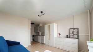 En moderne stue med sofa, spisebord og et køkken i baggrunden.