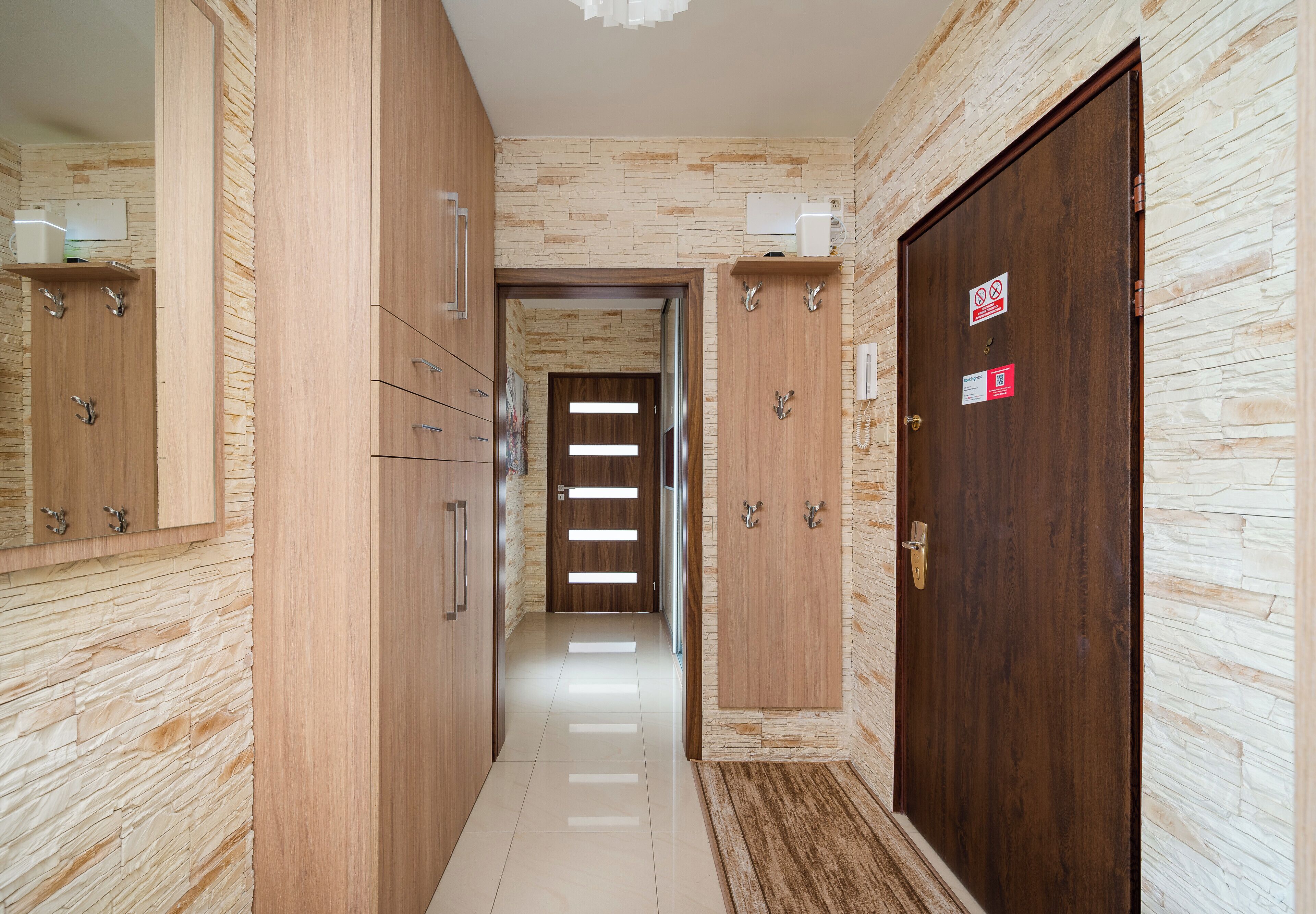 A hallway with wooden cabinets, a door with a sign, and a light fixture.