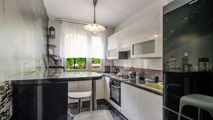 Une cuisine moderne avec un îlot central noir, des armoires blanches et une vue sur le paysage urbain par la fenêtre.