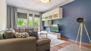 Un salon moderne avec un canapé, un téléviseur et un lampadaire sur trépied.