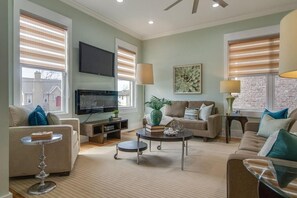 Ein Wohnzimmer mit Flachbildfernseher, zwei Sofas, einem Couchtisch und einer Lampe.