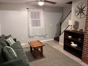 Ein Wohnzimmer mit einem grünen Sofa, einem Holztisch, einer Treppe und einem an der Wand befestigten Kompass.