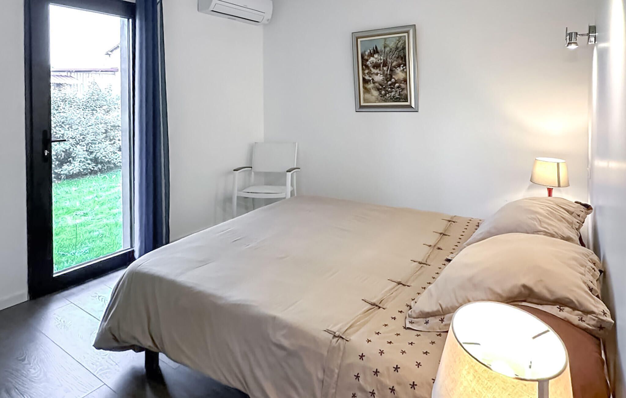 Une chambre à coucher avec un lit, une chaise, une lampe et un tableau au mur.