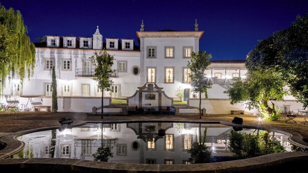 Un edificio grande y blanco con numerosas ventanas y un patio central con una fuente.