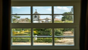 Una ventana con vista a un edificio que tiene una torre de campanas y un jardín bien cuidado.