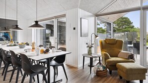 Ein modernes Interieur mit Essbereich, einer Couch und Blick durch eine Glastür.