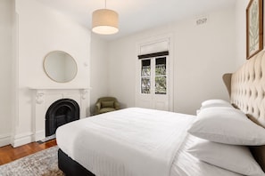 A bedroom with a bed, a fireplace, a window, and a hanging light fixture. - Stylish 3BR Terrace Near Sydney CBD & USYD (Darlington)