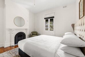 A bedroom with a bed, a round mirror, a fireplace, and a window with a view. - Stylish 3BR Terrace Near Sydney CBD & USYD (Darlington)