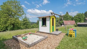 A play area with a sandbox, a small shed, and a yellow chair. - Lodge Trtinka /w Terrace & BBQ in Nature, Žalec, Slovenia (Žalec)