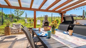 An outdoor patio with a grill, seating, and a view of the countryside. - Lodge Trtinka /w Terrace & BBQ in Nature, Žalec, Slovenia (Žalec)