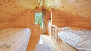 A wooden cabin with two beds, a window, and a view of the forest. - Lodge Trtinka /w Terrace & BBQ in Nature, Žalec, Slovenia (Žalec)